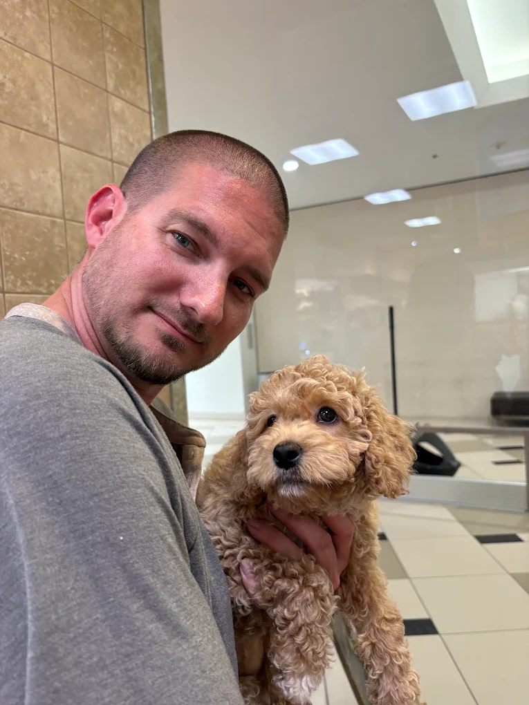 A man holding a curly-coated puppy